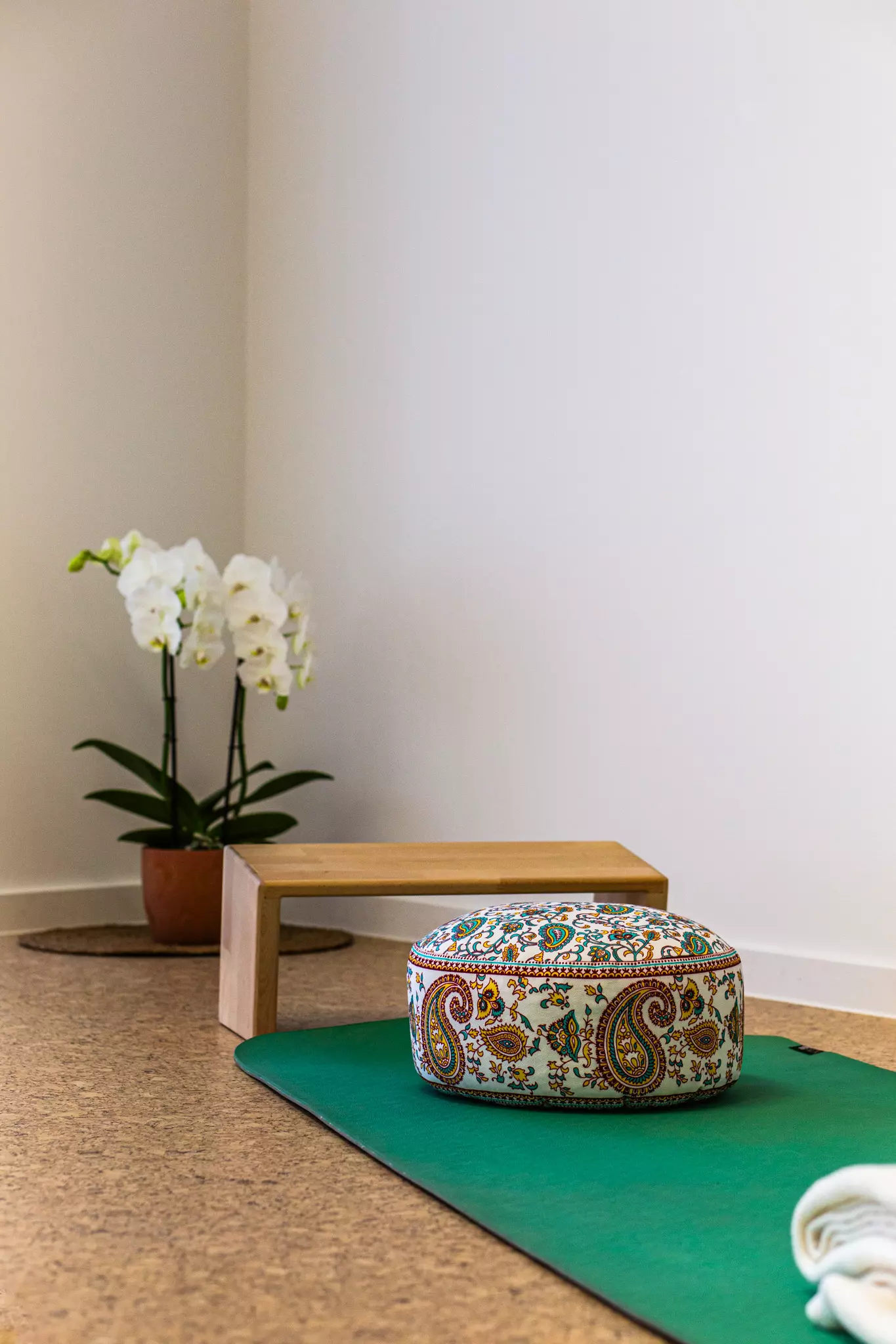 Yogamatte mit Kissen und einer Blume in der Ecke